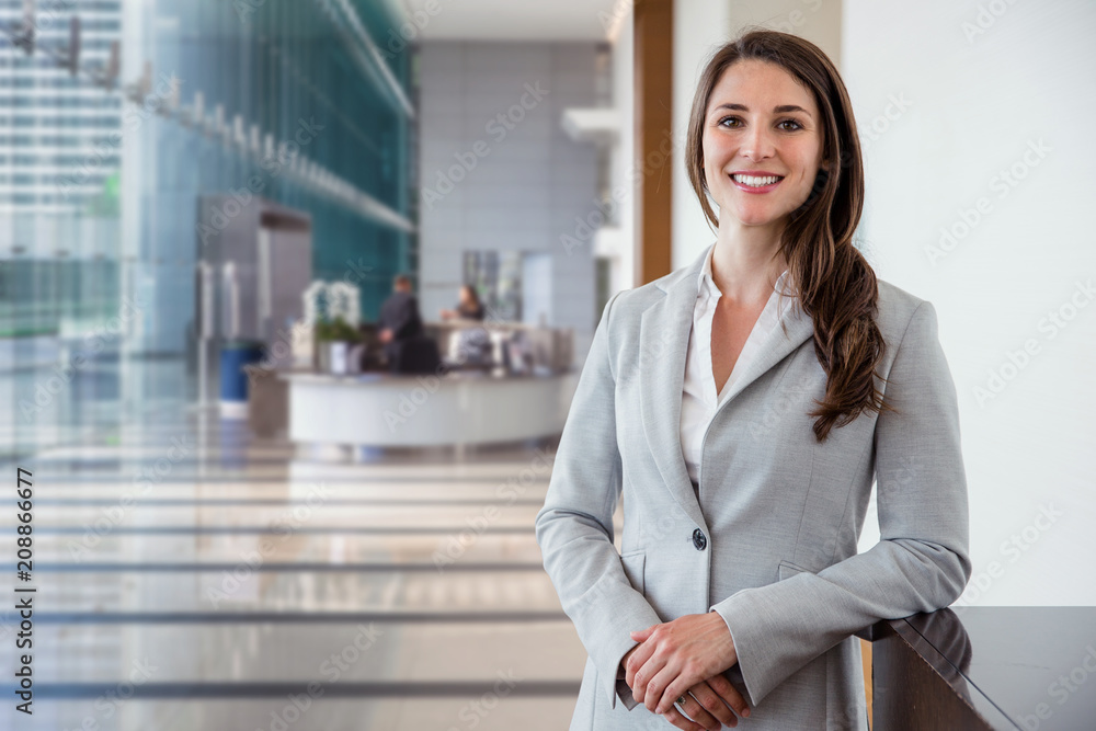 Cute commercial business corporate representative woman model brunette smiling in large building hall lobby - obrazy, fototapety, plakaty 