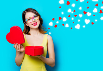 portrait of beautiful young woman with heart shaped gift on the wonderful blue studio background and abstract hearts