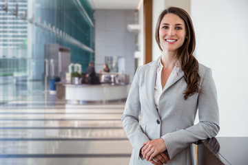 cute commercial business corporate representative woman model brunette smiling in large building hal