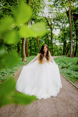 A refined bride in a white dress poses in the park