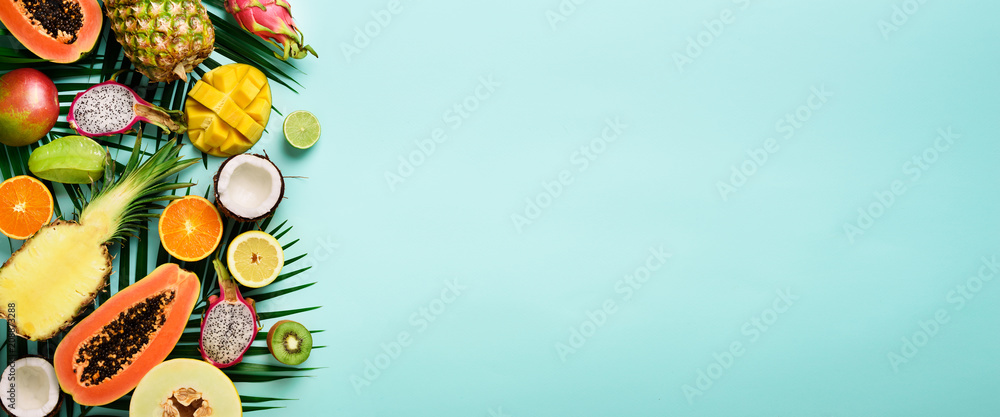 Exotic fruits and tropical palm leaves on pastel turquoise background - papaya, mango, pineapple, banana, carambola, dragon fruit, kiwi, lemon, orange, melon, coconut, lime. Banner. Top view. - obrazy, fototapety, plakaty 