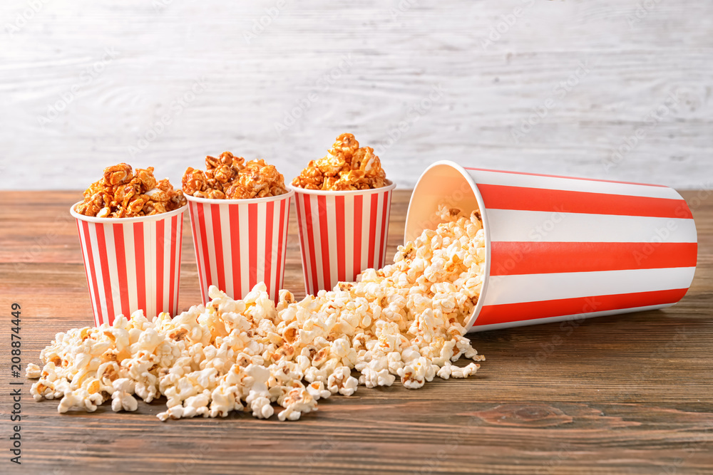 Cups with tasty popcorn on wooden table