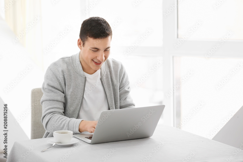 Young man working with laptop at table in cafe