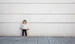 © David Pereiras - Little girl with sportive look posing in front of a modern white stone wall