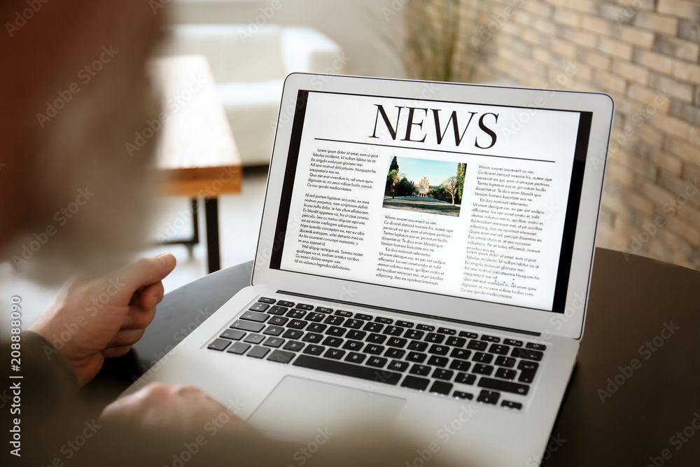 Senior man reading news on laptop screen in cafe, closeup