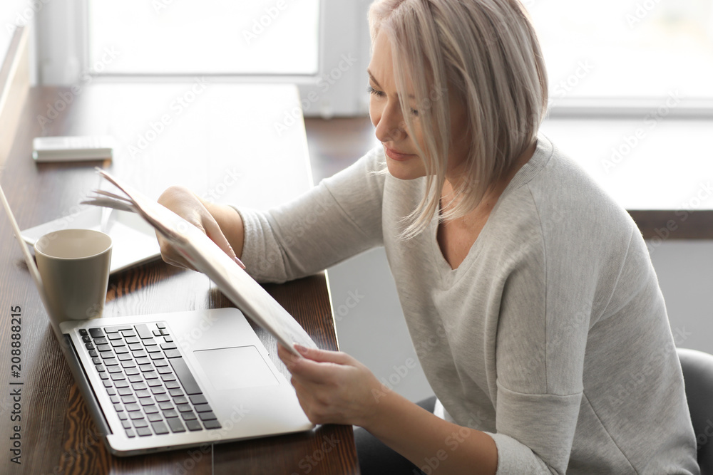Mature woman reading newspaper in cafe
