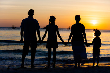 Silhouette of happy family having fun on the beach at the sunset time.