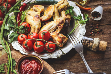 fried chicken wings in metal old plate. tomatoes and spices. wooden background