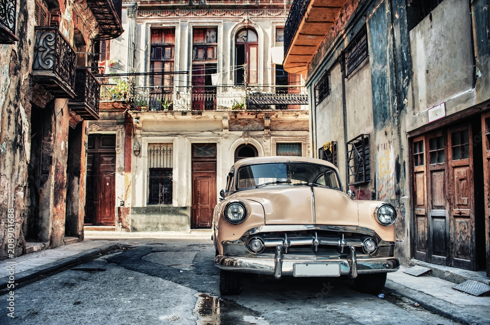 Old classic car in a street of havana with buildings in background - obrazy, fototapety, plakaty 