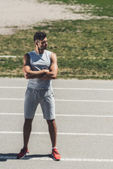 Wall Mural - serious young man with crossed arms on running track