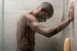side view of handsome young african american man washing body in shower
