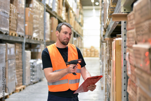 logistician in a warehouse of a forwarding agency scans packages for dispatch // Arbeiter in einer Spedition im Warenlager - Transport von Gütern im Onlinehandel