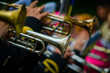 An orchestra in black uniform playing trumpets outdoors. Musical instruments closeup with blurred background