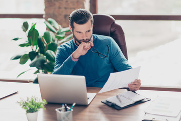 Attractive, handsome, professional accountant in casual outfit holding report in hand, took off glasses with thoughtful, concentrated expression looking at paper, having problem, trouble