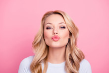 Portrait Of Cute Lovely Girl In Casual Outfit With Modern Hairdo Sending Blowing Kiss With Pout Lips Looking At Camera  Isolated On Pink Background. Affection Feelings Concept