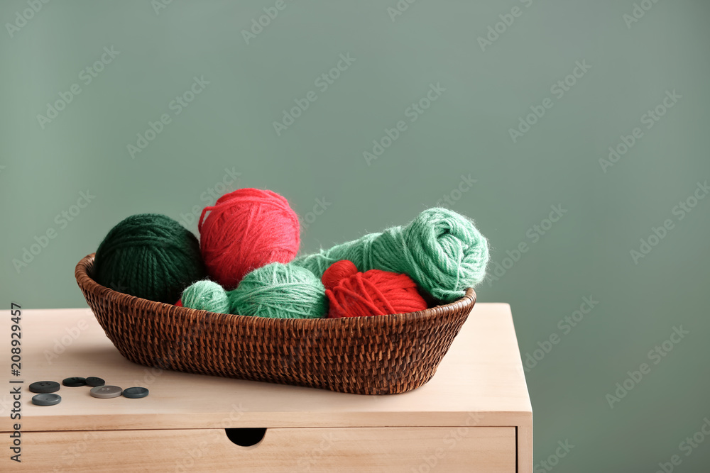 Wicker basket with knitting threads on wooden table