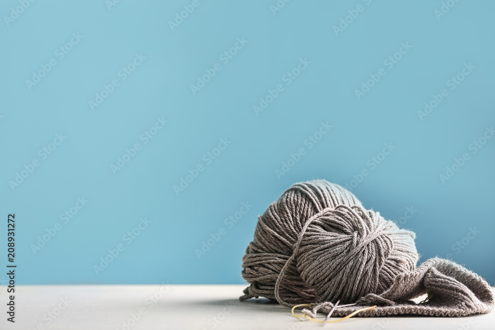 Knitting yarn on table against color background