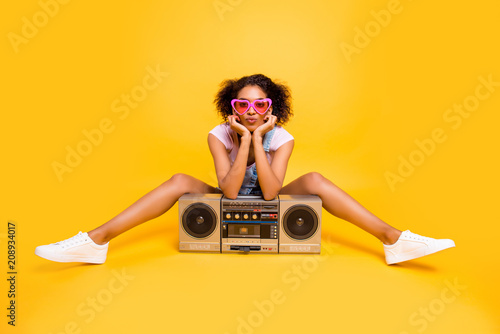 Zdjęcie XXL Portret seksownej uroczej dziewczyny w okularach o boom box, wysyłając pocałunek z dąsami usta w aparacie na białym tle na żółtym tle. Koncepcja odpoczynku wypoczynek relaks