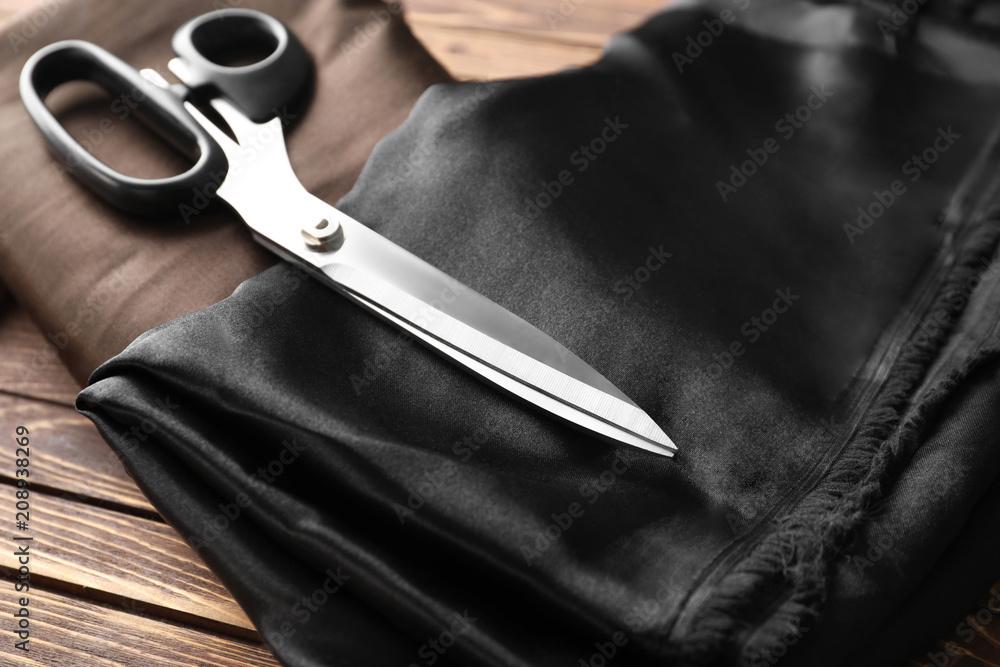 Pieces of cloth and scissors on wooden background