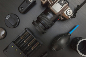 Wall Mural - Top view of work space photographer with dslr camera system, camera cleaning kit, lens and camera accessory on black table background. Hobby journalism photography technology art concept