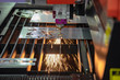 Close-up of the CNC laser cutting machine cutting the metal plate with the sparking light. Modern sheet metal manufacturing process.