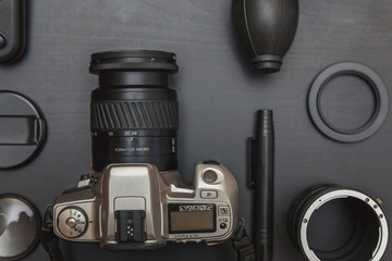 Wall Mural - Top view of work space photographer with dslr camera system, camera cleaning kit, lens and camera accessory on black table background. Hobby journalism photography technology art concept