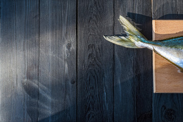 Tail of fresh sea fish on a wooden table, free space.