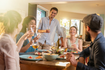 Mixed group of friends having fun while sharing a meal 