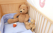 Ein großer und ein kleiner Teddybär sitzen in einem Kinderbett