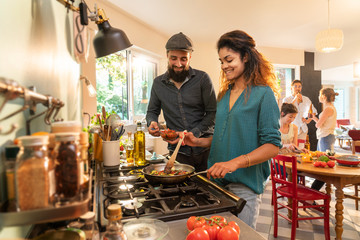 Mixed group of friends have fun while cooking a meal in kitchen