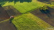 Aerial view from the drone, a bird's eye view of agricultural fields with a road through and a tractor on it in the spring evening at sunset