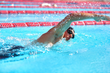 Wall Mural - Triathlon fitness athlete man training cardio swimming in outdoor pool at stadium. Swimmer man swmming in blue water . Sport and fitness exercise.