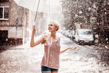 Outdoor Portrait Of Young Beautiful Happy Smiling Girl Holding Transparent Umbrella, Posing Under Rain In Street Of European City