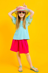 Wall Mural - Girl with red hair on a yellow background. A charming girl in bright summer clothes made herself horns.