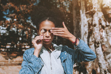 Charming Black Girl In A Denim Jacket And With A Curly Afro Hair Is Standing Outdoor And Closing Both Of Her Eyes With The Chamomile In A Right Hand And Another Eye Simply With A Left Hand, Autumn Day