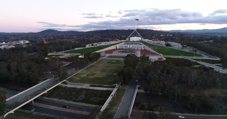 Wall Mural - Capitol hill in government district of Canberra at sunset in aerial panning in front of new parliament house under national flag.
