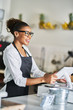 © Joshua Resnick - friendly african american shop assistant using pos terminal to input orders at restaurant