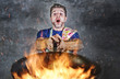 © TheVisualsYouNeed - shocked messy man with apron holding pan in fire burning the food in kitchen disaster and unskilled and unexperienced terrible home cook