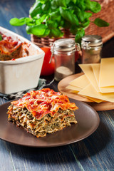 Wall Mural - Piece of tasty hot lasagna with spinach on a plate