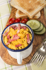 Wall Mural - scrambled eggs with roasted bacon in an enamel mug