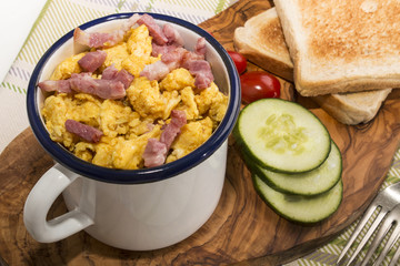 Wall Mural - scrambled eggs with roasted bacon in an enamel mug