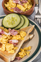 Wall Mural - scrambled eggs with fried bacon, toasted bread and sliced cucumber