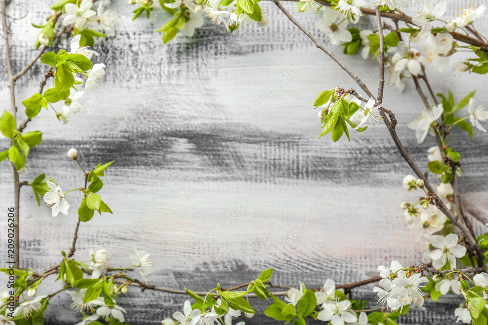 Frame made of beautiful blossoming branches on wooden background