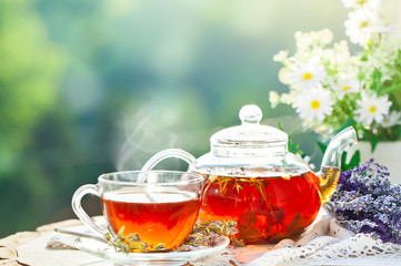 Cup with hot tea with mint and a thyme on a wooden table in a summer garden. Selective focus,