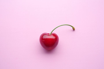 closeup of one cherry on pink background