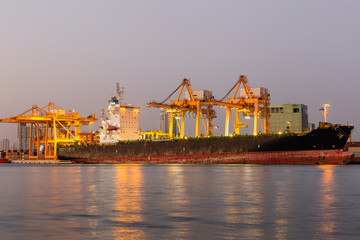 Port authority Shipping working loading containers by crane in ship on the night