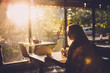 Young female student sitting in modern coffe shop. Sunset.Woman sitting in front of the window in  cafe.
