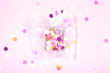 Wall Mural - One box with colorful confetti on pink background. Festive card. Top view.