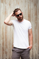 Wall Mural - Hipster handsome male model with beard wearing white blank t-shirt with space for your logo or design in casual urban style