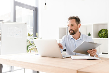 Successful businessman holding folder while sitting